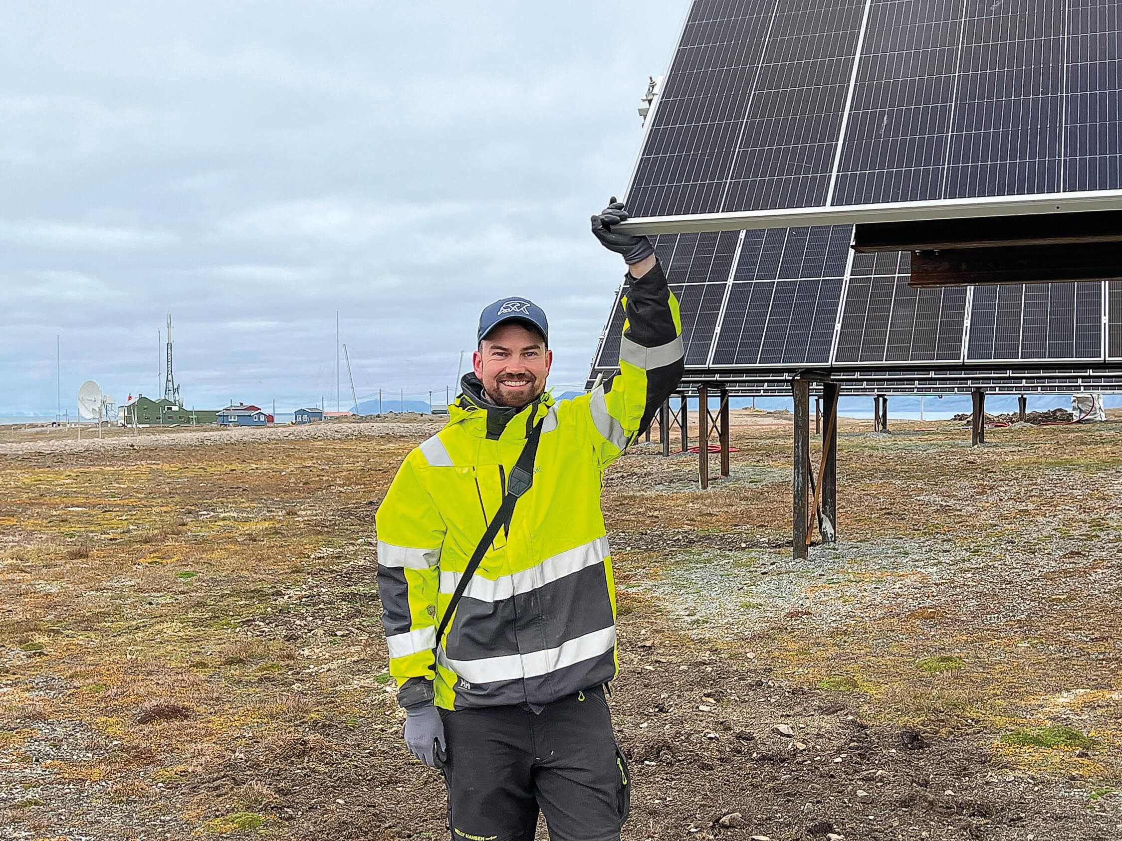 Photo of a man next to solar panels in Svalbard.