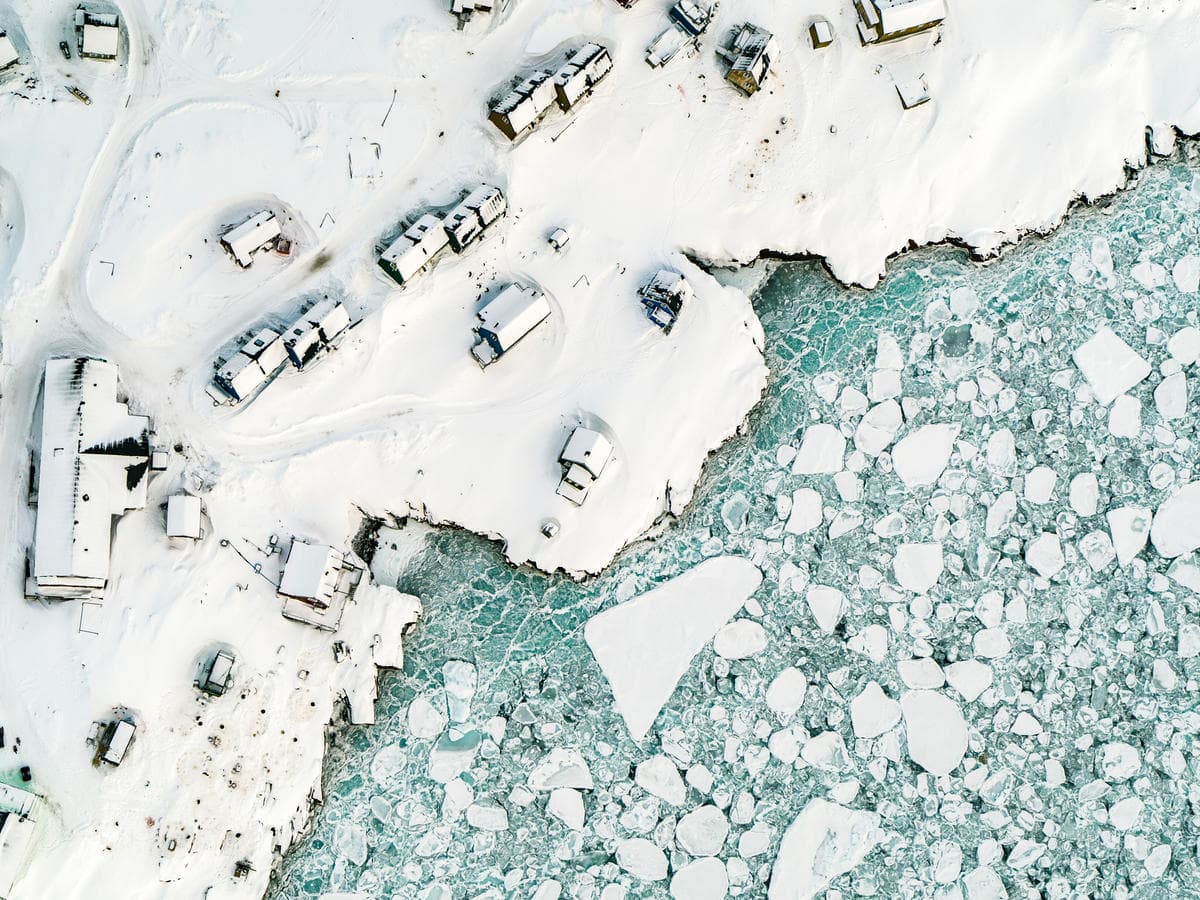 The remote Arctic town of Ittoqqortoormiit, East Greenland. This is an aerial shot of brightly coloured houses along the coast.