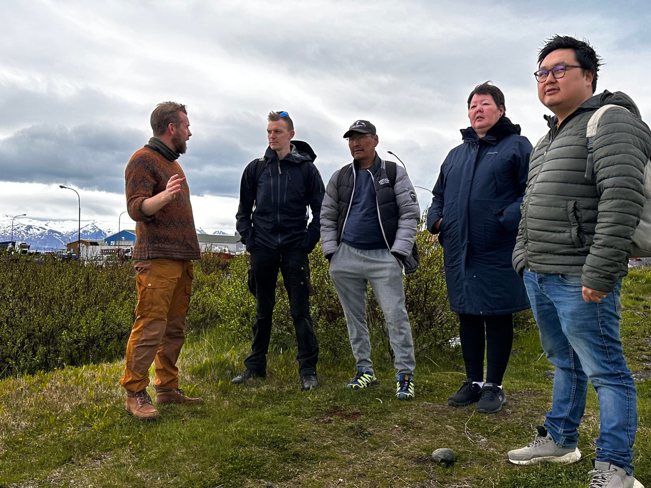 A group of men standing and talking dressed for temperature approximately 15 °C.