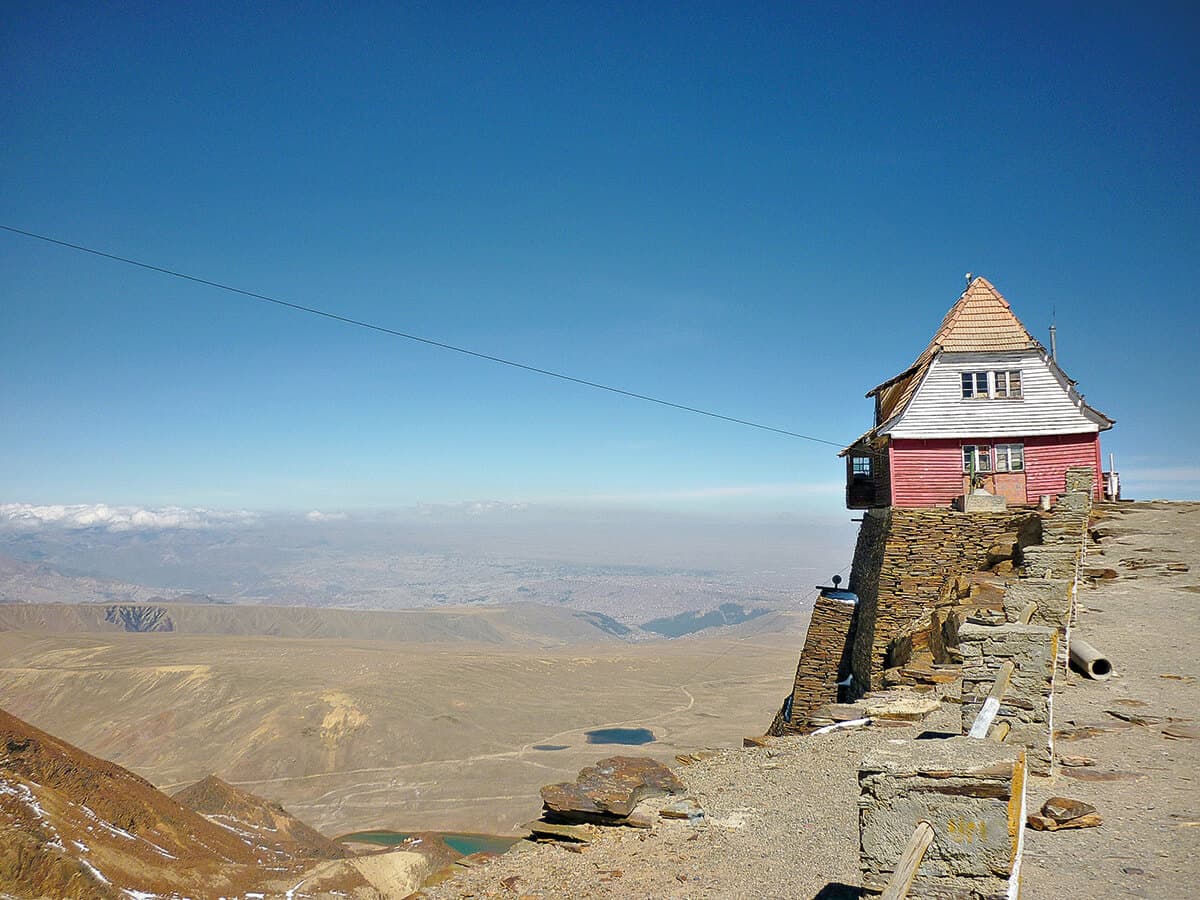 Ski resort building on top of a mountain looking over a landscape without any snow.