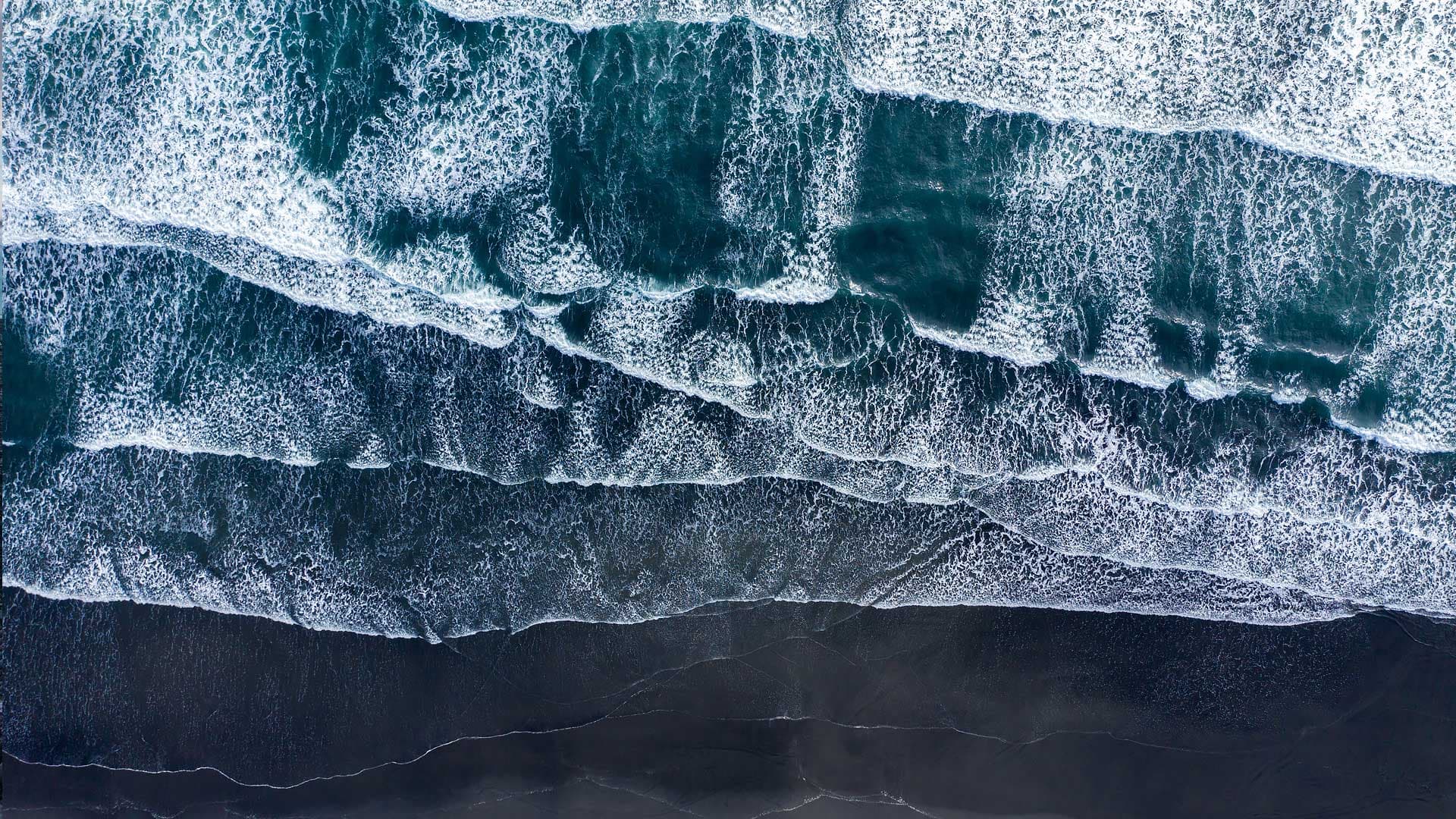 Aerial drone view of Atlantic ocean waves washing black basaltic sand beach, Iceland