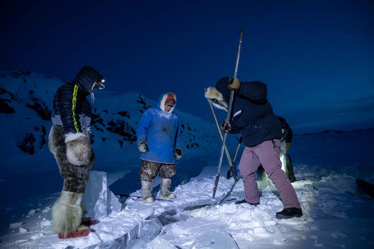 WWF staff, Erica Guth (in purple pants), tries her hand at breaking off a chunk of lake ice by continuously driving the pick into the thick ice at an angle. As local Inuit Guardians stand by, a final satisfying blow dislodges a large chunk ready to be harvested and brought back for the Elders to make tea with.