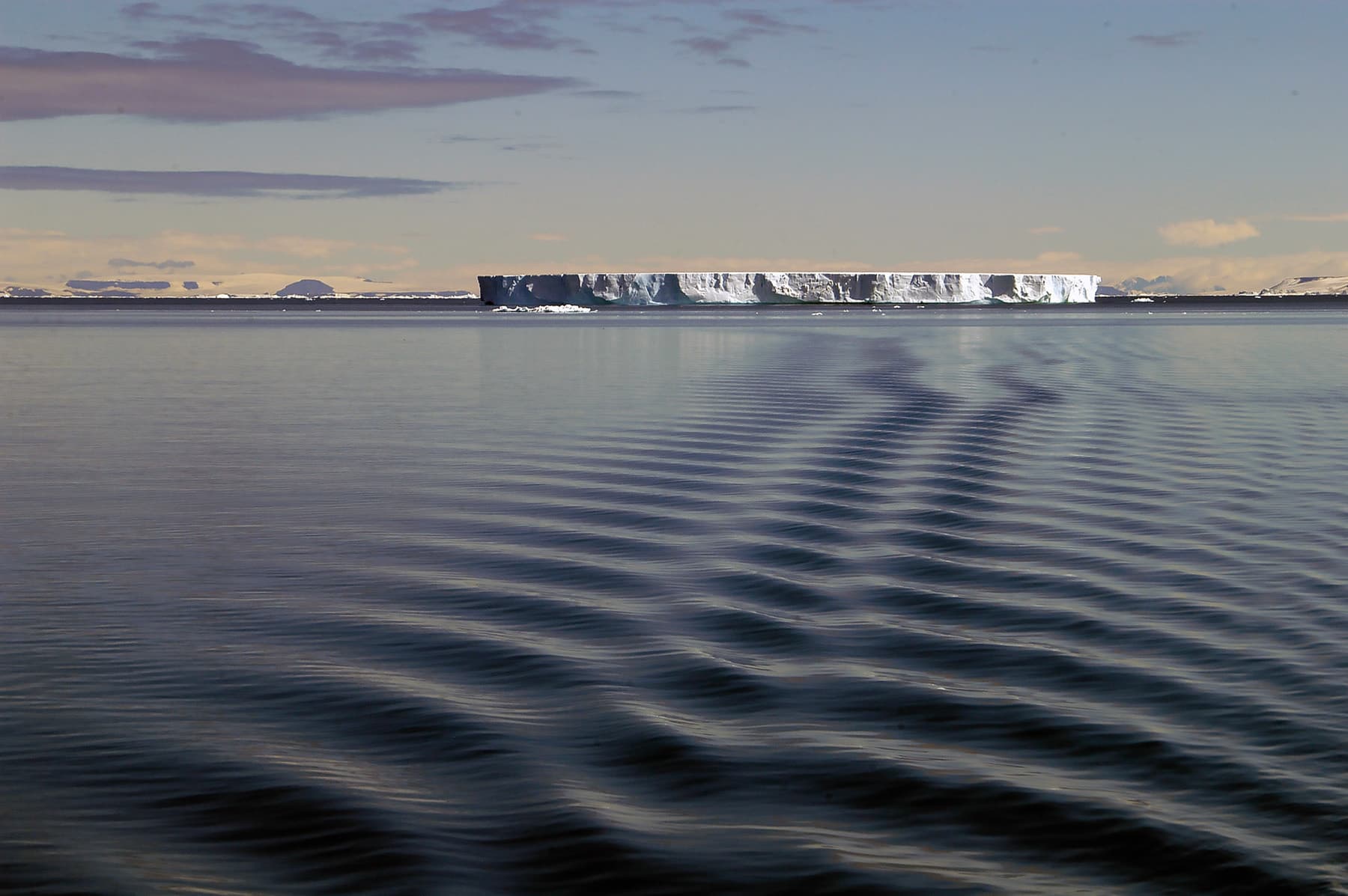 Massive iceberg floating. in dark, cold water in low light.