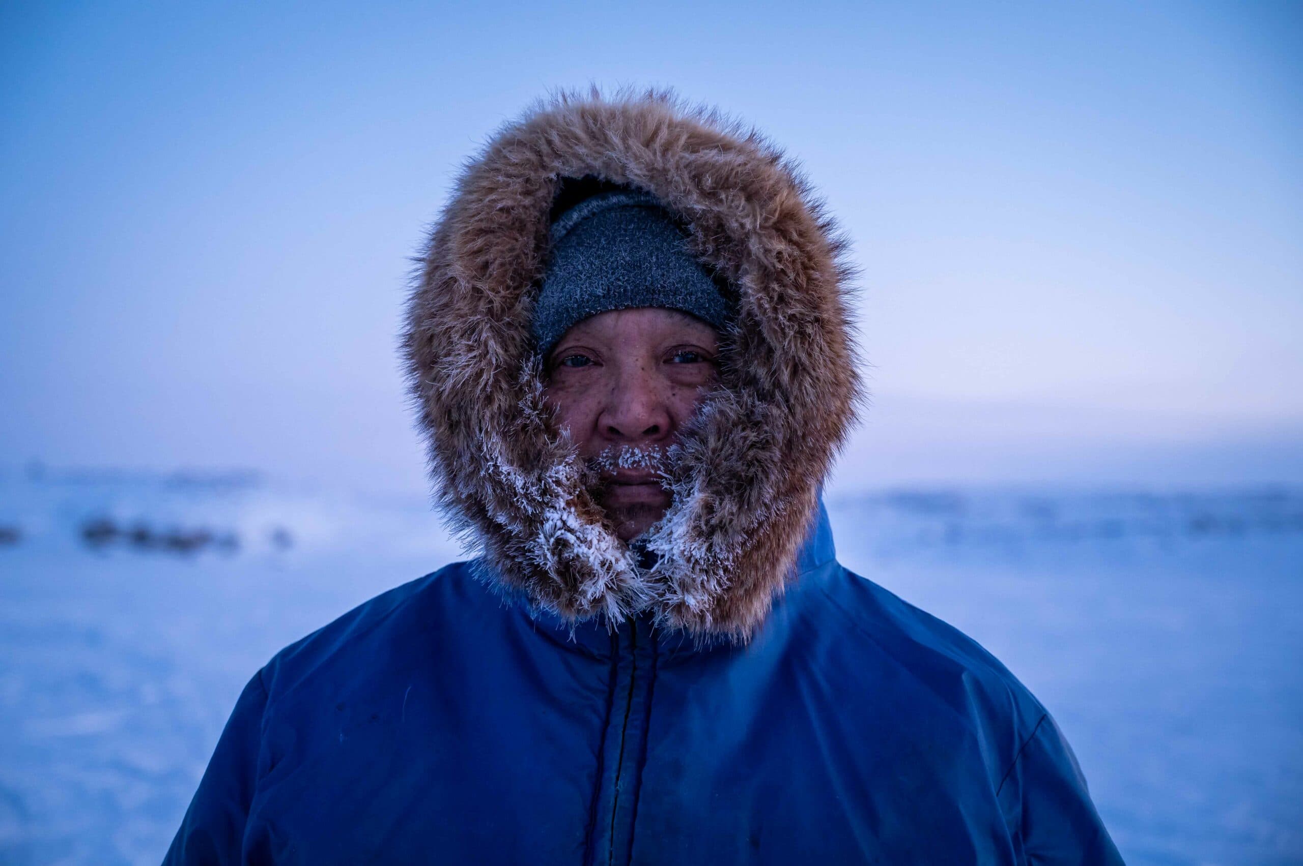 Man standing in Arctic Canada with a warm jacket with a frost covered hood.