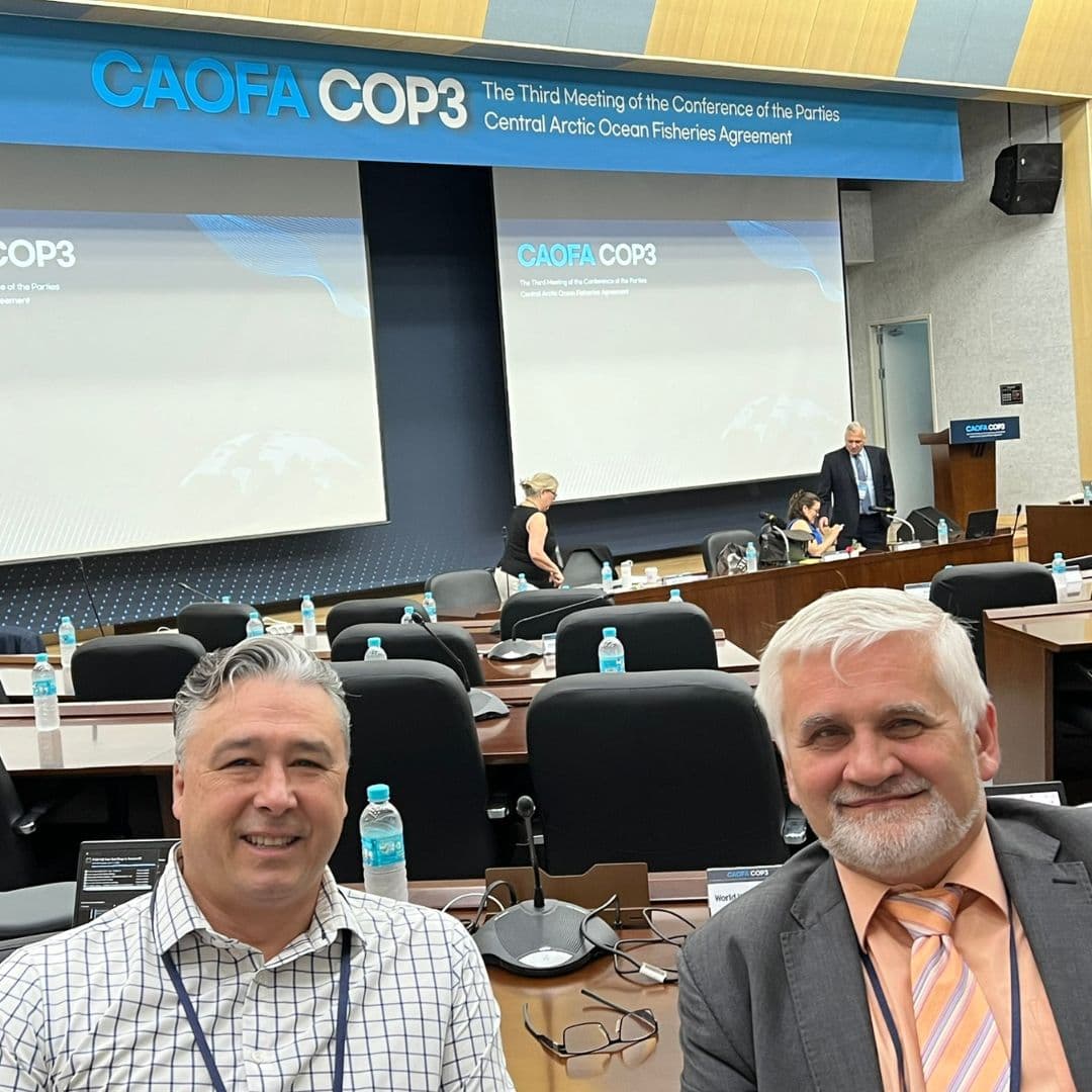 Two men at sitting in a conference venue for the Central Arctic Oceans Fisheries Agreement conference of the parties.