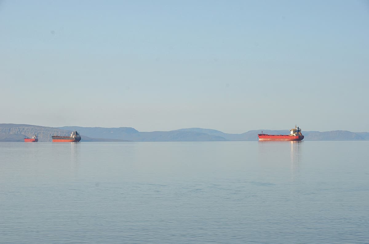 Shipping carriers anchored in Eclipse Sound waters surrounded by mountains.